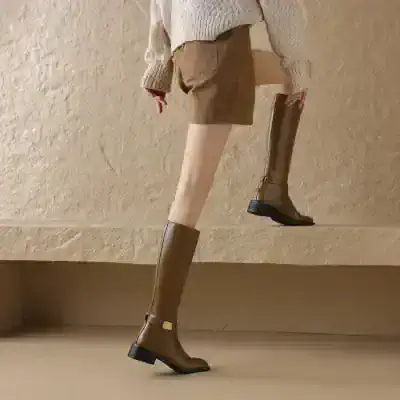 Elegant knee-high leather boots displayed on a model, perfect for fall and winter fashion, showcasing Monalisa store’s premium footwear collection.