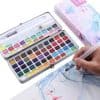 Colorful watercolor paints palette with brush on art drawing paper for creative painting art supplies.