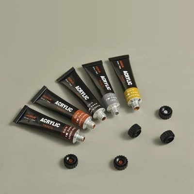 Varnished acrylic paint tubes with caps and assorted paint cap covers, suitable for art projects and fine detail work, displayed on a neutral background.