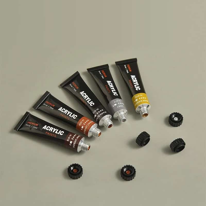 Varnished acrylic paint tubes with caps and assorted paint cap covers, suitable for art projects and fine detail work, displayed on a neutral background.