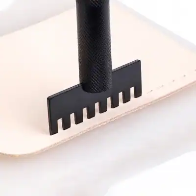 Precision woodworking carving tool with textured black handle on beige wood surface.