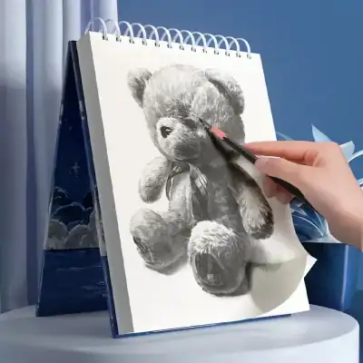 Teddy bear sketch artwork on sketchbook, art supplies for drawing, detailed pencil drawing of plush toy, creative art project, artistic Teddy bear illustration, Monalisa Medical opt product imagery, high-quality art craft image, creative sketching with professional pencils, detailed black and white teddy bear drawing, art therapy and drawing hobby inspiration.