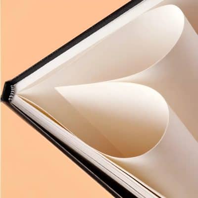 Elegant book with cream-colored pages showing heart-shaped cutouts, placed against a soft peach background, representing ideas of health, wellness, and elegance at Monalisa Store.