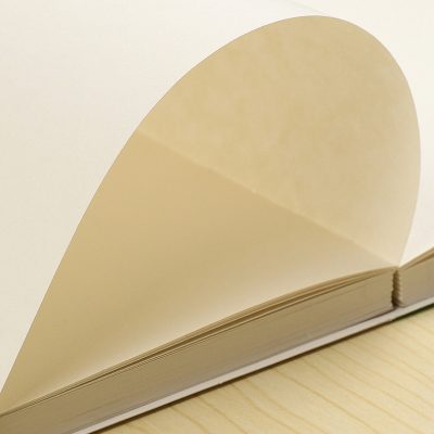 Heart-shaped cream paper page from a notebook on a wooden surface, representing love, thoughts, or creativity in medical and optical contexts.