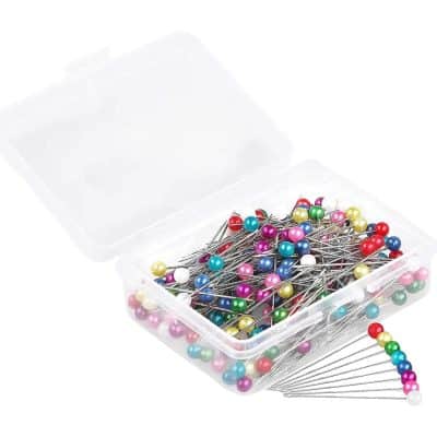 Colorful sewing pins in a clear plastic box for tailoring and craft projects.