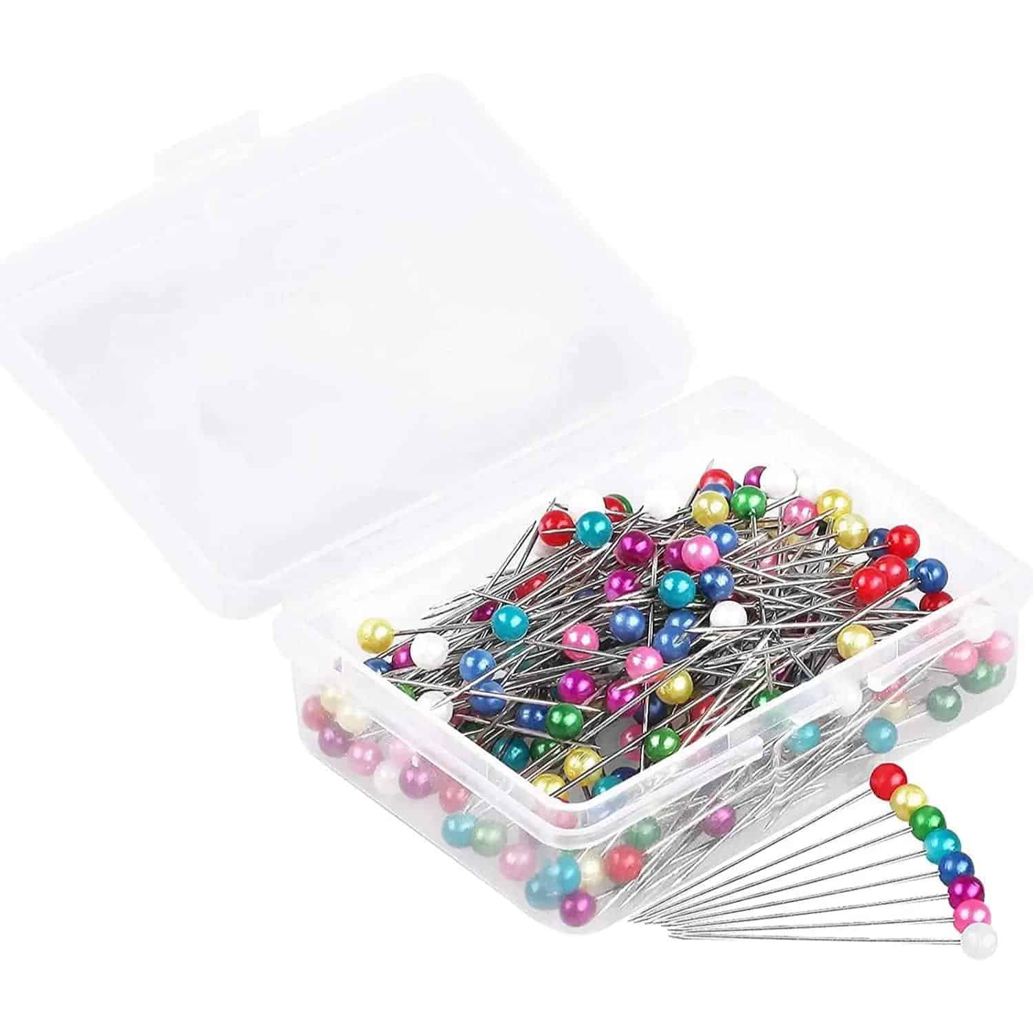 Colorful sewing pins in a clear plastic box for tailoring and craft projects.