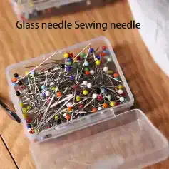 Colorful glass sewing needles with pinned heads in a plastic storage box, ideal for sewing, tailoring, and craft projects. Perfect for precision sewing tasks and detail work.