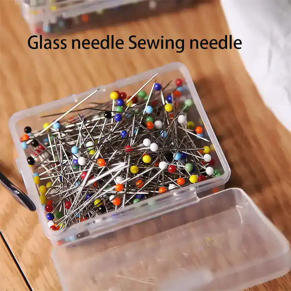 Colorful glass sewing needles with pinned heads in a plastic storage box, ideal for sewing, tailoring, and craft projects. Perfect for precision sewing tasks and detail work.