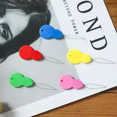 Colorful whale-shaped sewing pins for fashion and textile design, assorted in blue, red, yellow, green, and pink, featured on a Monalisa Store magazine cover with a black and white portrait.