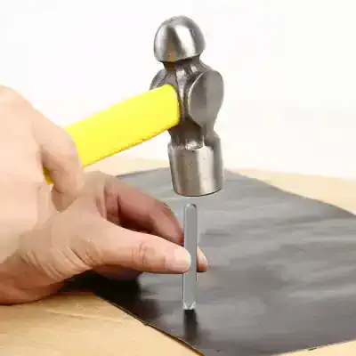 Hammer tapping a small chisel into leather material for crafting or repair, showcasing tools used in leatherworking or upholstery.