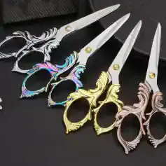 Silver, gold, and rose gold scissors with ornate handles, perfect for hairstyling or salon use, displayed on a dark surface.