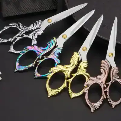 Silver, gold, and rose gold scissors with ornate handles, perfect for hairstyling or salon use, displayed on a dark surface.