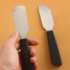 Stainless steel spatula and butter knife with black ergonomic handles for precise cooking and food safety. Perfect for professional kitchens and home use.