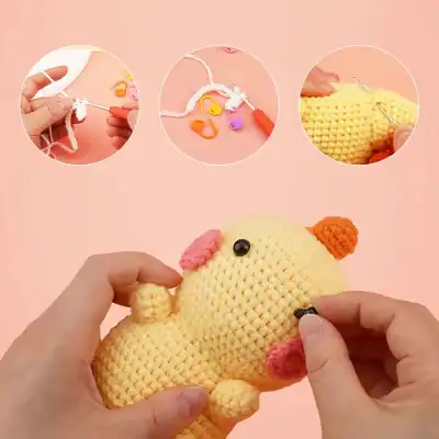 Colorful crochet chick plush toy in process on pink background with crochet tools and yarns.