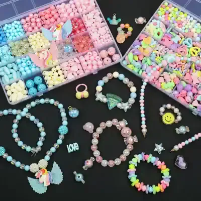 Pastel-colored jewelry making beads and charms for kids and DIY accessories, organized in plastic containers on a black background.