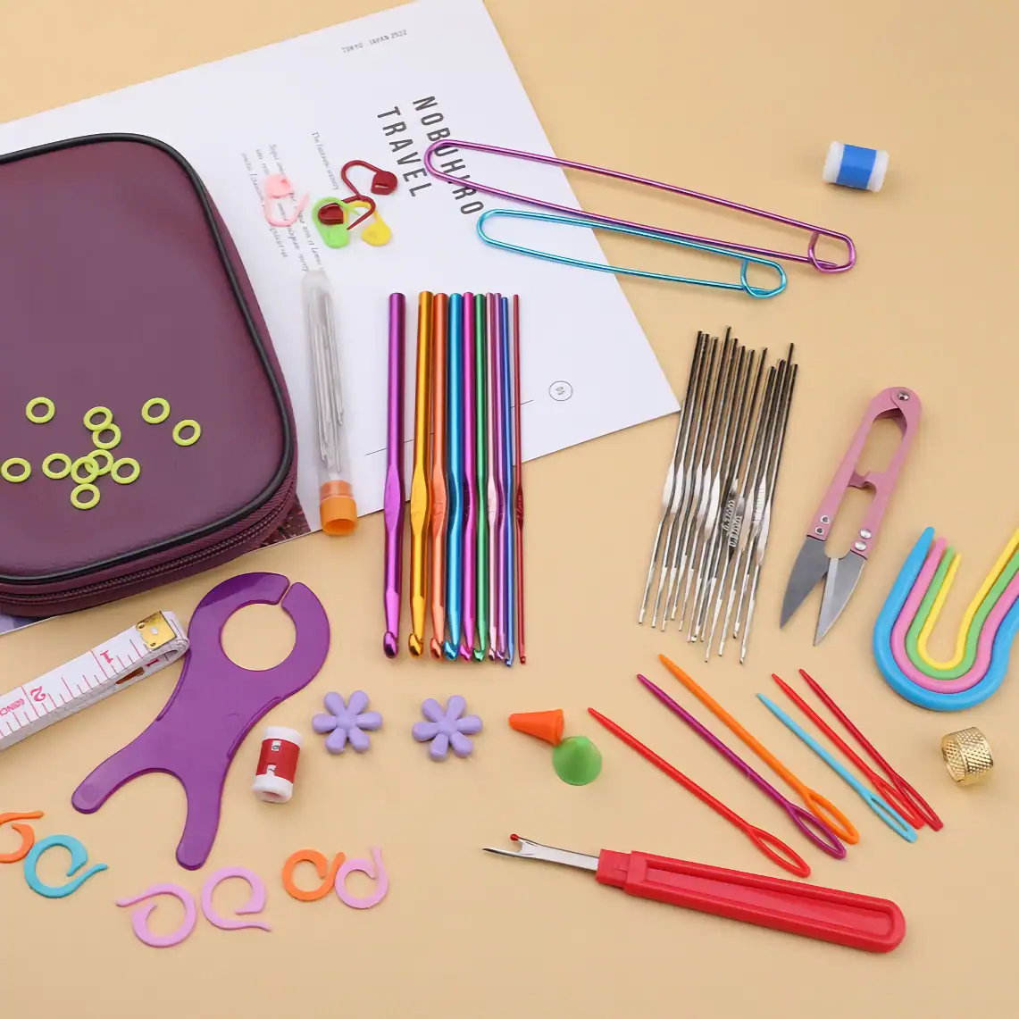Colorful crochet hooks, scissors, stitch markers, and sewing accessories arranged on a light beige surface, showcasing premium quality crafting tools at Monalisa Store, ideal for knitting and crochet projects.