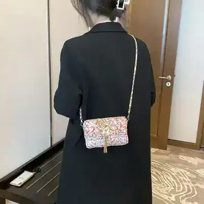 Elegant floral patterned crossbody clutch bag with zipper and tassel, perfect for accessory enhancement and casual to formal outfits.