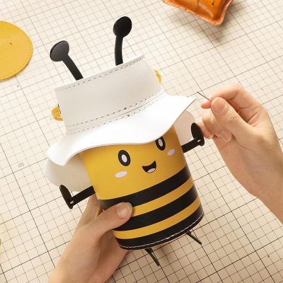 Cute bee-themed storage container with a white hat lid, perfect for organizing small items. Fun and functional design, ideal for kids' rooms or playful office decor.