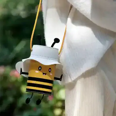 Cute bee-shaped handbag with a white hat lid accessory, designed for kids, featuring a cheerful face and black striped body, perfect for playful fashion and accessories.