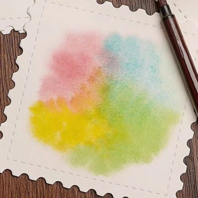 Colorful watercolor on a white textured paper with decorative edges, placed on a wooden surface with a brown pen nearby, embodying artistic creativity and vibrant expression for optical health and wellness.