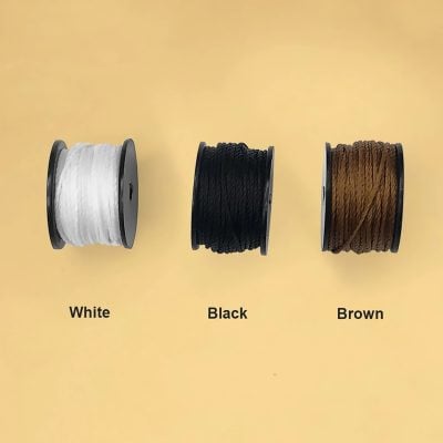 Spools of colorful embroidery thread in white, black, and brown displayed against a plain yellow background. Perfect for textile and sewing projects, highlighting high-quality materials from Monalisa Medical Store.