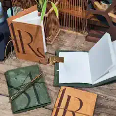 Decorative notebooks with gold pen and organizational accessories on wooden table, showcasing Monalisa Store's premium stationery collection for professional and personal use.