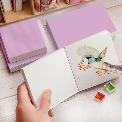 Aesthetic watercolor sketchbook with bird illustration, pastel pink and purple notebooks, and watercolor paints, perfect for journaling and artistic projects at Monalisa Store.