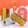 Shiny gold and silver metallic threading spools displayed on a festive pink background with decorative gift bags, perfect for enhancing monalisa store's opt and jewelry product presentation.