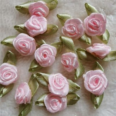 Pink satin rose appliqué embellishments with green satin leaves for clothing, accessories, or craft projects. Perfect for adding a floral touch to garments, decorations, and DIY fashion designs.