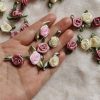 Delicate pink and cream satin rose floral embellishments with green ribbon leaves, ideal for wedding decorations, dress accessories, or craft projects for a luxurious touch.
