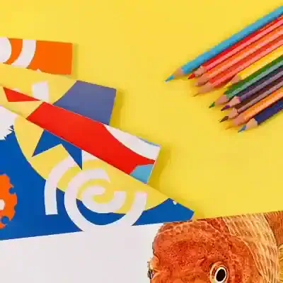 Brightly colored crayons and paper with creative design elements on a yellow background, perfect for children’s art supplies and stationery from Monalisa Store.