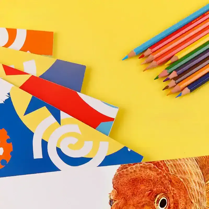 Brightly colored crayons and paper with creative design elements on a yellow background, perfect for children’s art supplies and stationery from Monalisa Store.