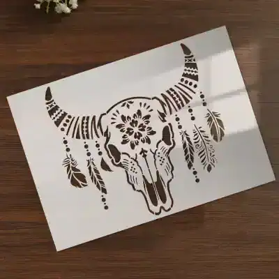 Intricate black and white buffalo skull with feather and floral designs, art stencil for wall decor, ideal for bohemian or eclectic interior styles.