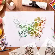 Vibrant butterfly stencil art with floral patterns on white paper, surrounded by watercolor paints, brushes, and art supplies, showcasing creative painting techniques at Monalisa Store.