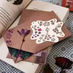 Elegant butterfly-themed floral cutout paper craft on a textured pink envelope with dried flower accents, perfect for personalized stationery or decorative art.