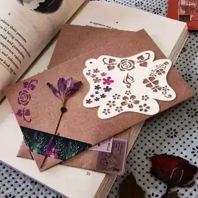 Elegant butterfly-themed floral cutout paper craft on a textured pink envelope with dried flower accents, perfect for personalized stationery or decorative art.