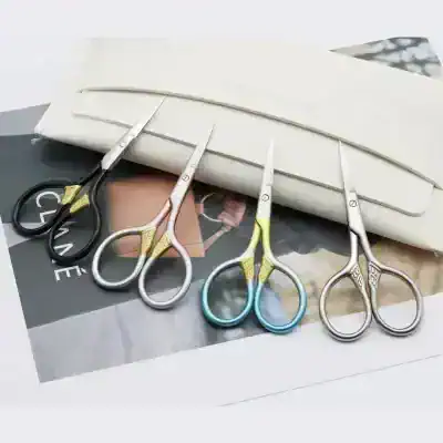 Miniature scissors with colorful handles on fashion magazines, ideal for fashion design and tailoring, showcasing precision and style in sewing and craft projects.