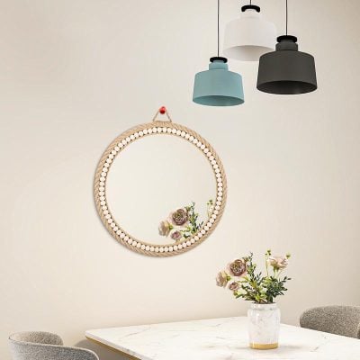 Elegant interior decor with a round mirror, pastel-colored pendant lights, and a floral arrangement in a modern vase, perfect for a stylish optometry or eyewear store display.