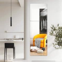 Mirror reflection of a modern living space with an orange armchair and wardrobe in the background, emphasizing stylish home decor and interior design elements.