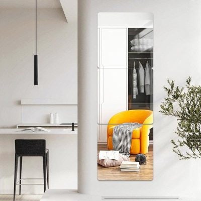 Mirror reflection of a modern living space with an orange armchair and wardrobe in the background, emphasizing stylish home decor and interior design elements.