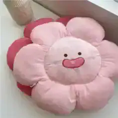 Soft pink flower-shaped plush cushion with a cute smiling face, perfect for kids' rooms or cozy decor.