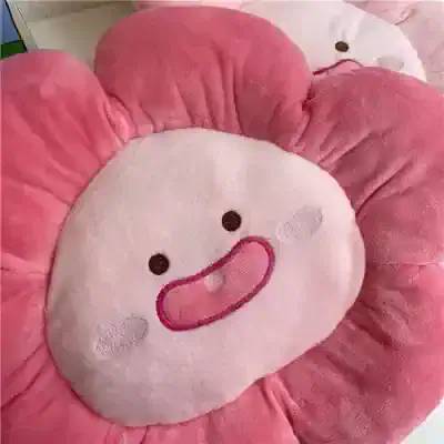 Cute pink flower-shaped plush pillow with a smiling face, perfect for kids and home decor. Soft and comfortable, ideal for bedroom accessories or playful gifts.