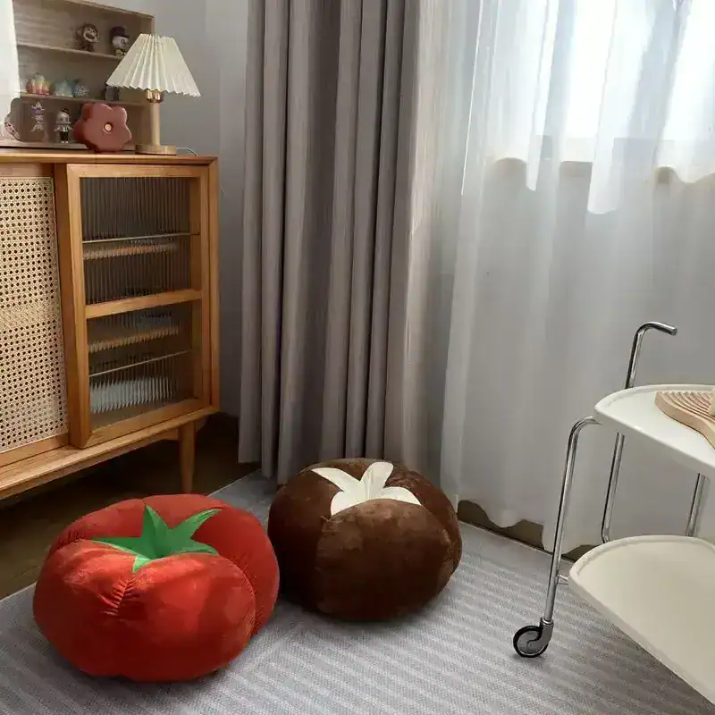 Plush tomato and pumpkin-shaped cushions in cozy bedroom corner, with natural light, bedside cabinet, and decorative accessories for comfortable living and stylish interior design.