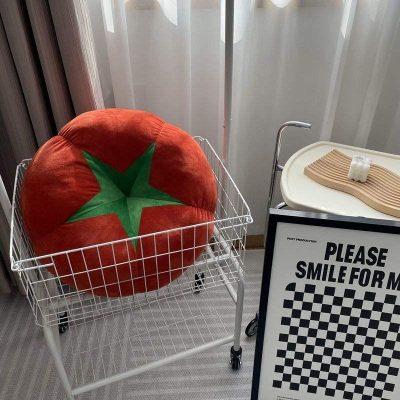 Soft plush tomato-shaped pillow in a shopping cart at Monalisa Store, emphasizing fun and comfort for eye care customers.