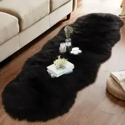 Luxurious black faux fur rug on a wooden floor with elegant candles and floral decor, perfect for upscale interior design and home decor inspiration.