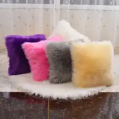 Vivid faux fur throw pillows in purple, pink, gray, yellow, and white arranged on a white fluffy rug for home decor, showcasing luxurious design and vibrant colors.