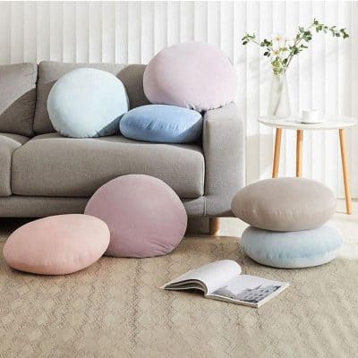 Soft pastel-colored cushions on a beige sofa in a modern living room, perfect for comfortable seating and home decor.