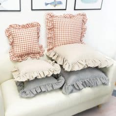 Soft throw pillows with ruffled edges in beige, gray, and gingham checkered patterns, perfect for cozy home decor and bedroom accents.