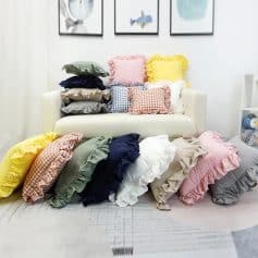 Colorful ruffled pillow collection displayed on a white sofa in a cozy living room.