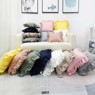 Colorful ruffled pillow collection displayed on a white sofa in a cozy living room.